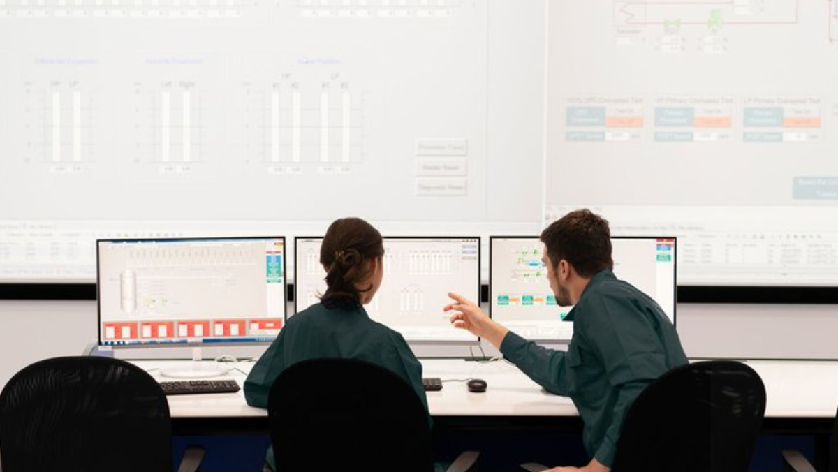 Operators working with multi-screen dashboard displaying oilfield analytics.