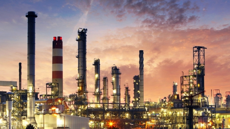 Illuminated oil refinery complex with distillation towers at sunset