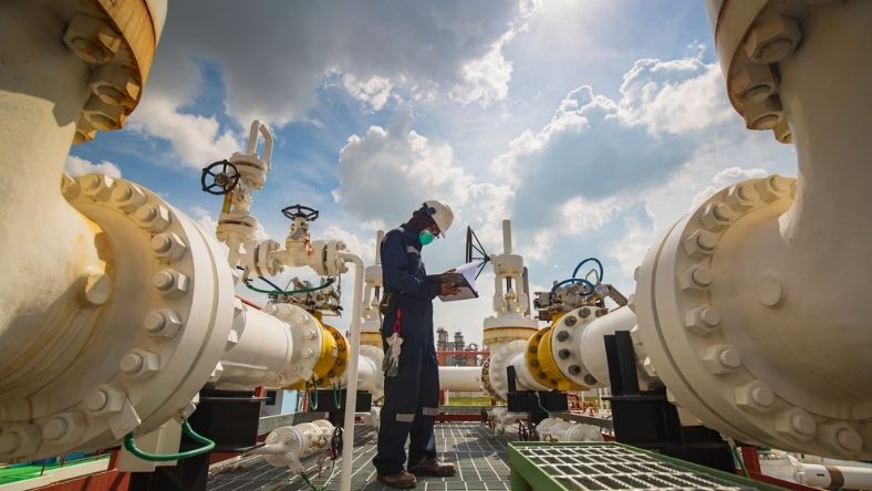 Oilfield engineer inspecting smart pipeline sensors and valves