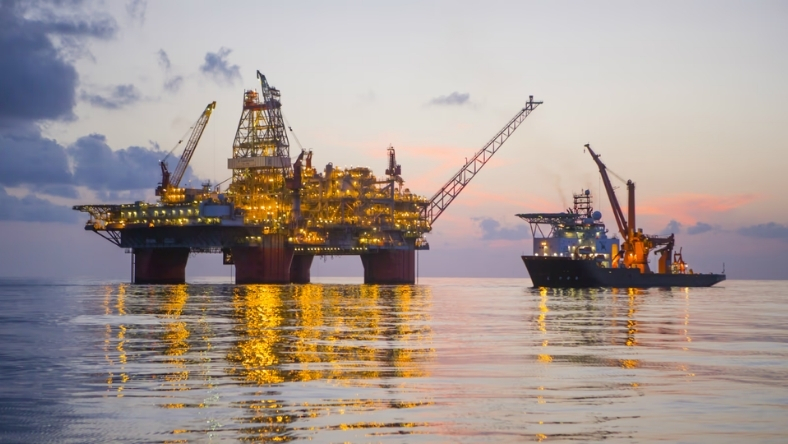 Offshore oil platform and service vessel operating at sunset